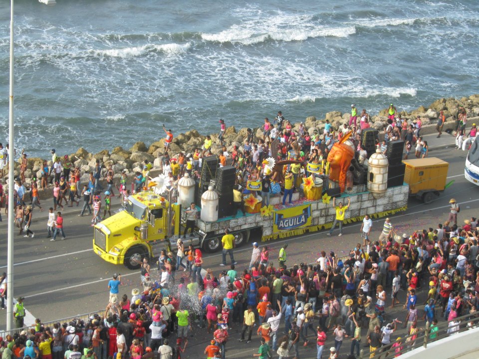 Photo showing a truck with partiers and people on the street watching the parade during the Cartagena Independence Festivities.