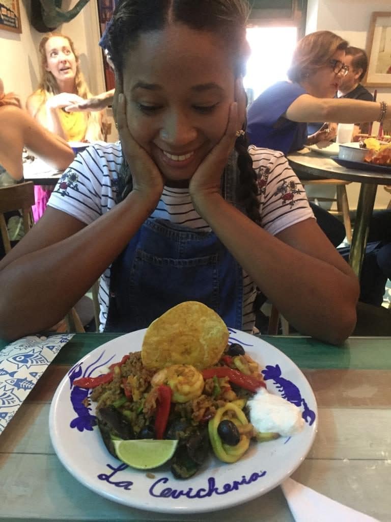 Photo of a girl looking down excitedly at a plate of seafood rice, the next thing on our list of local dishes to try in Cartagena.