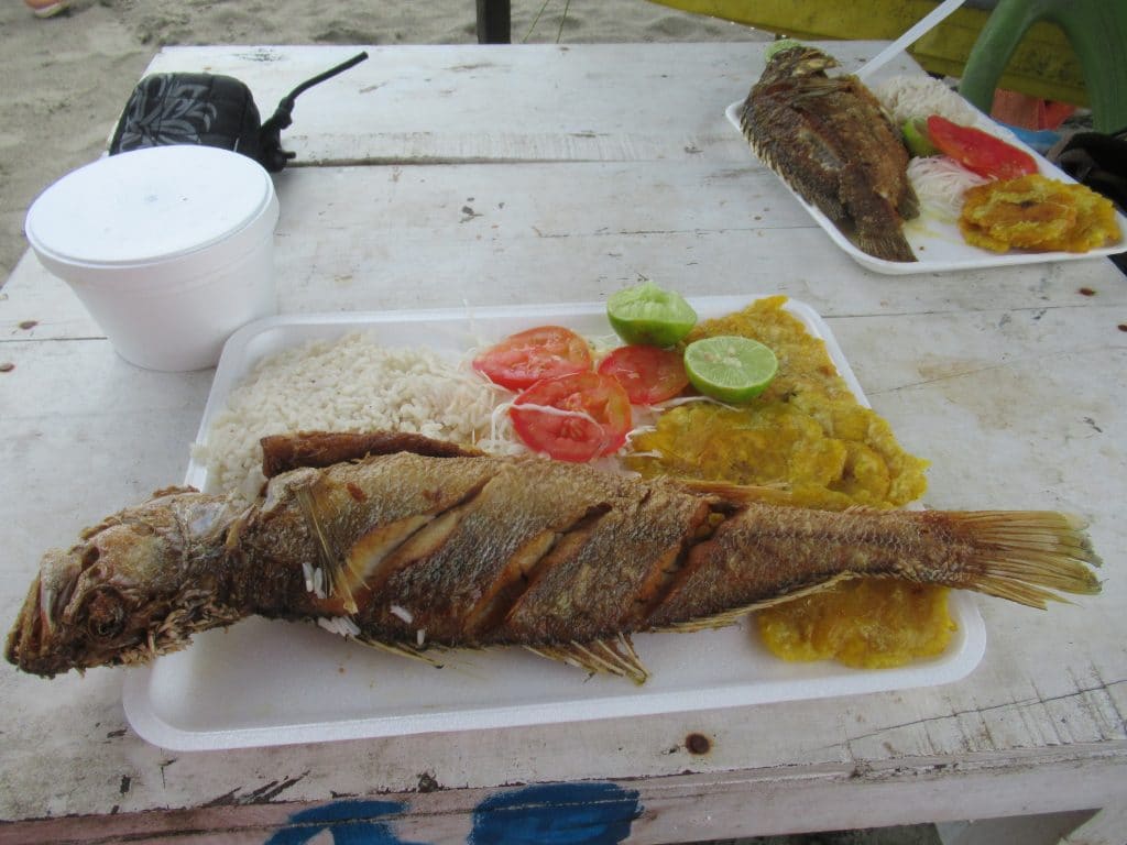 Photo of a plate with a fried fish, patacones, rice, and salad, number 1 on the list of traditional foods to try in Cartagena.
