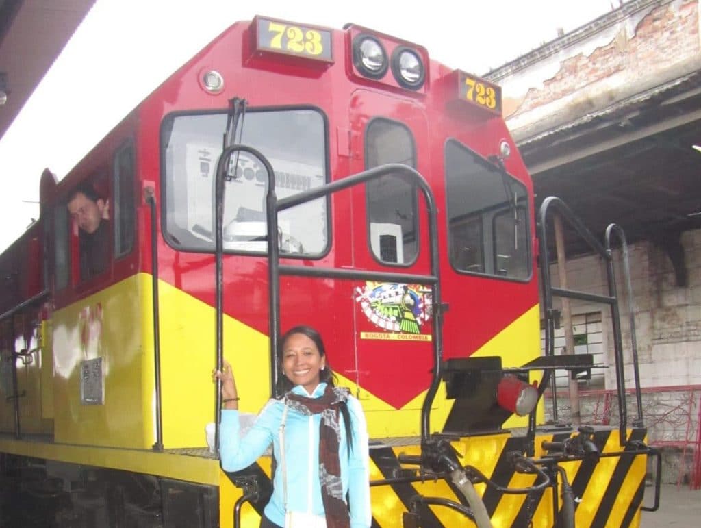 A girl standing on the train engine on the train in Bogotá.