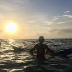 Photo of a girl sitting in a hammock over the water with the sunset in the background in the Colombia San Bernardo Islands