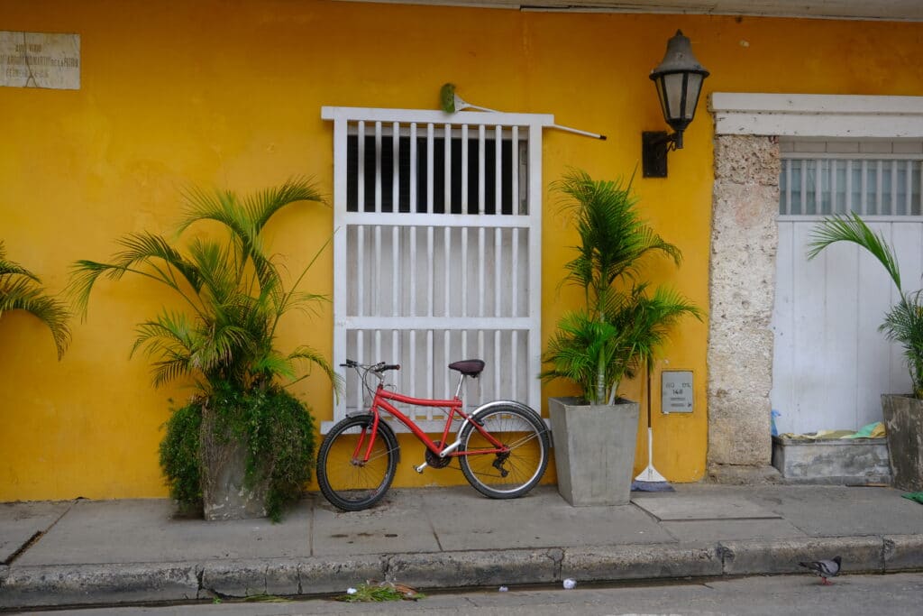Photo of a bike next to a yellow building with white wooden window in Cartagena Colombia.