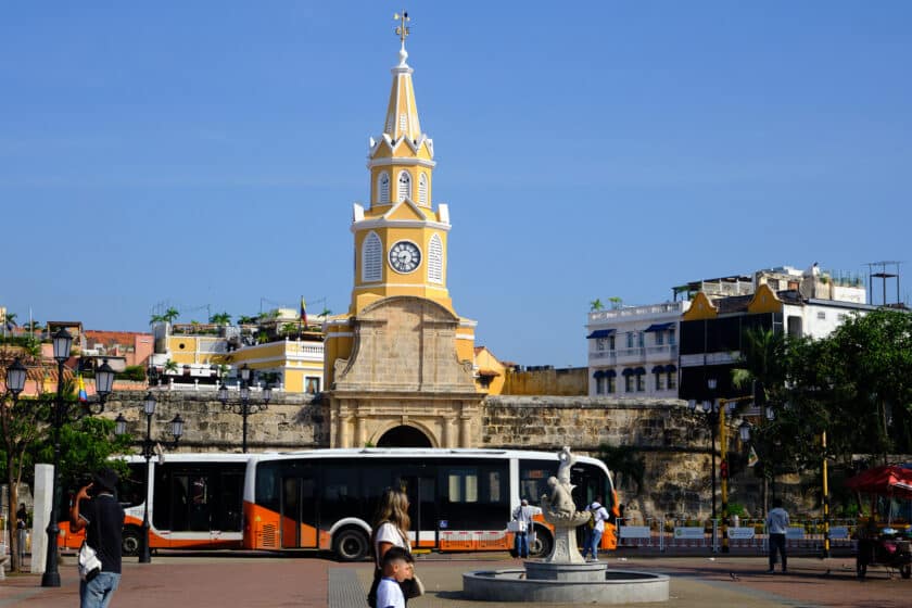 Two buses for public transportation in Cartagena, Colombia passing in front of the clocktower.