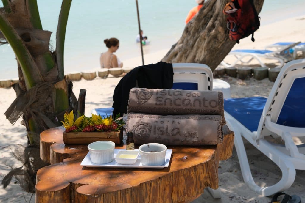 Photo of some towels on a table in front of the beach with the name Isla del Encanto on them.