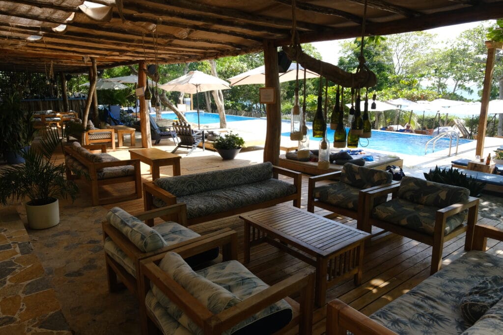 Foto de unas mesas y sofas con una piscina al fondo.