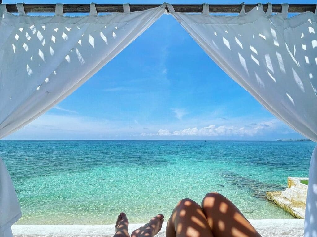 Photo of a couple's feet on a beach bed in the Islas del Rosario Colombia with clear blue water in the background.