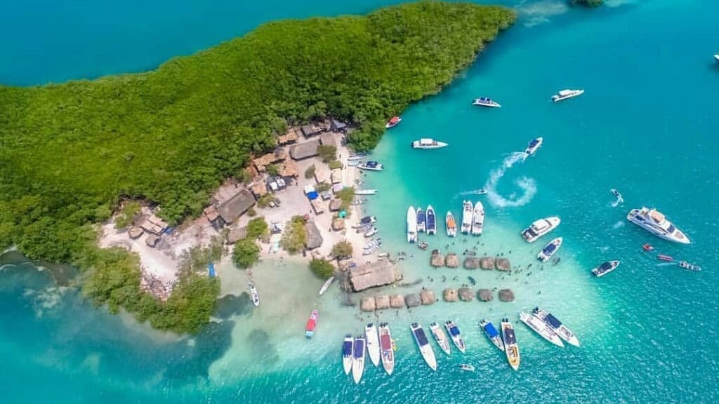 Aerieal photo of boats parked around a small beach area on an island covered by mangroves at Cholón in the Rosario Islands.