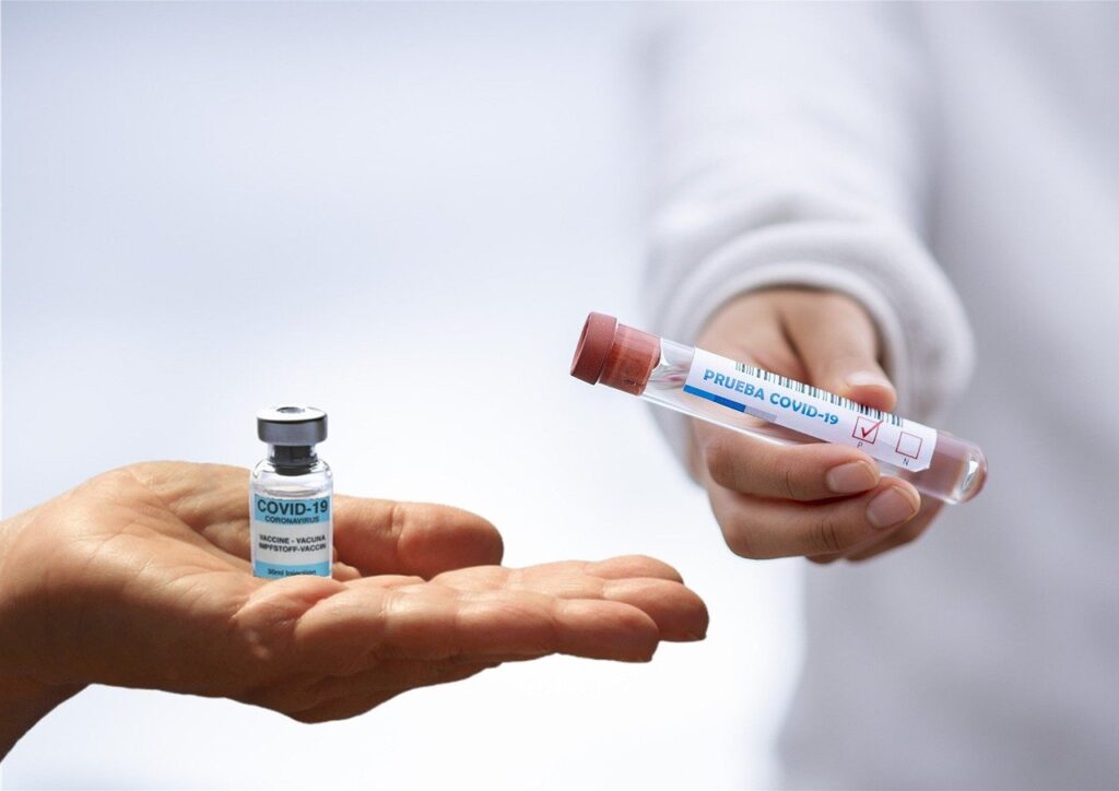 Photo of a hand with a vaccine vial and hand with a test tube for Covid testing in Cartagena.