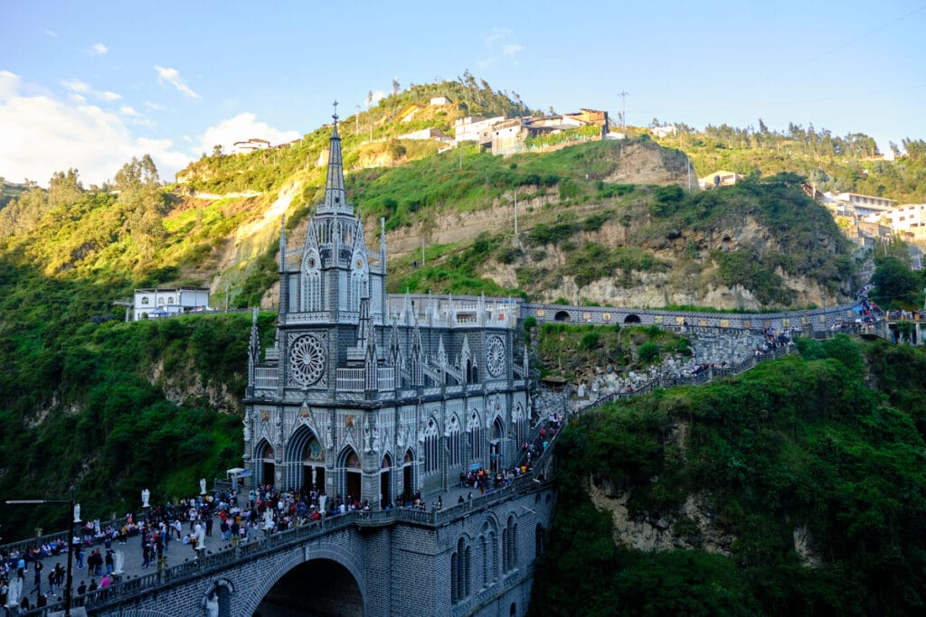 Photo of the virgen de las lajas cathedral columbia with people on the bridge and hill in the background