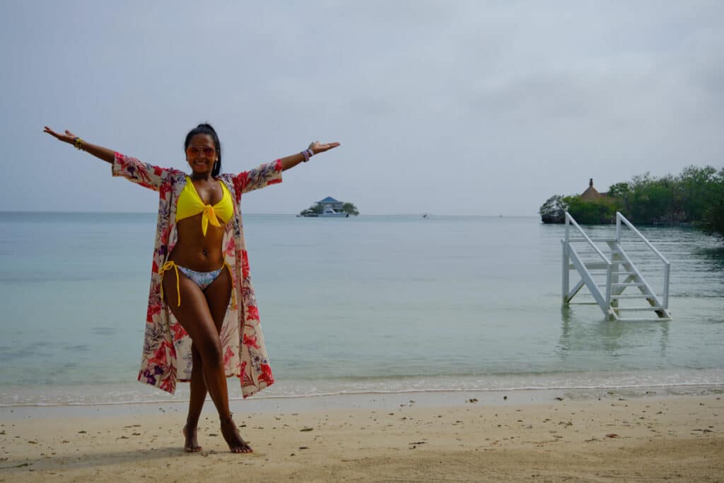 Photo of a girl on a beach raising her hands during an excursion in Cartagena's Rosario Islands.