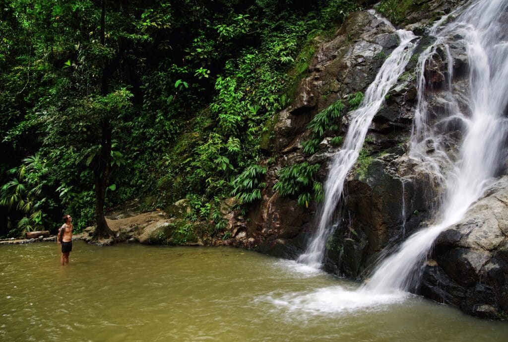 Photo of a guy staying at one of the Minca hotels looking at a waterfall.