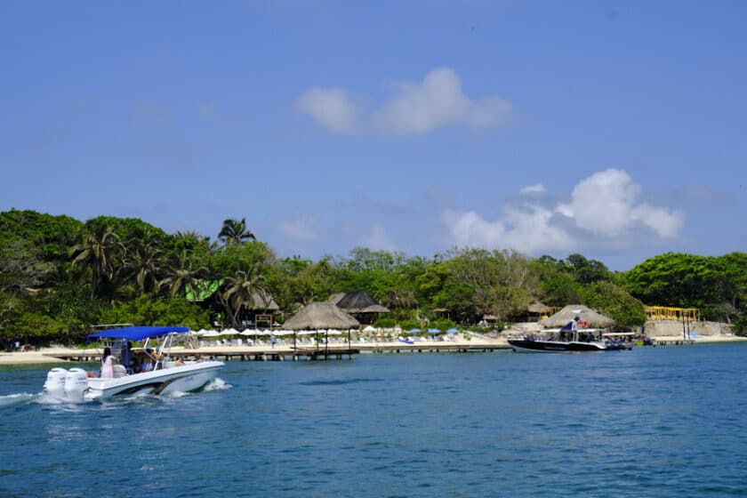 Un bote pasando por un muelle y playa durante un tour de las Islas del Rosario.