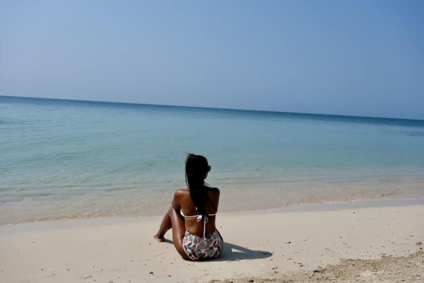Una mujer sentada en la playa viendo el mar durante un tour a las Islas del Rosario desde Cartagena, Colombia.