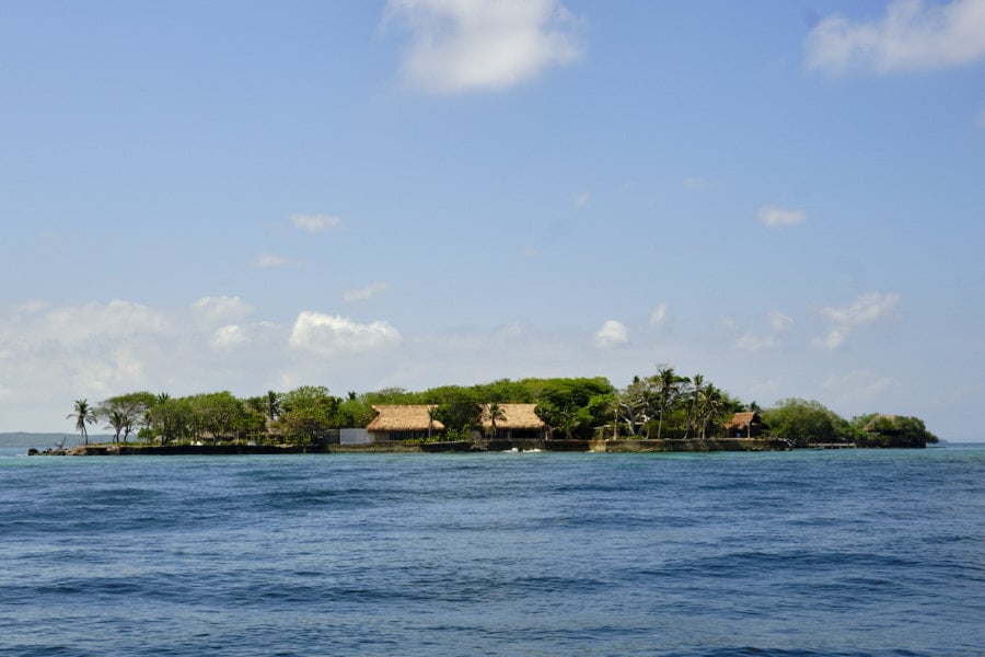 Photo of a small island in the Rosario Islands near Cartagena with some structures nestled among the trees.