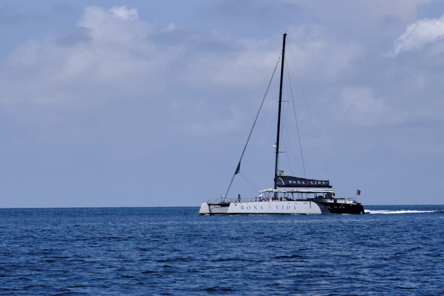 Photo of a Catamaran with lettering saying Bona Vida seen across the water.