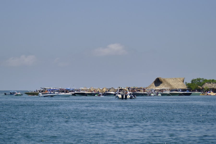 Photo of many boats parked on the water around some covered areas at Cholón in the Rosario Islands.