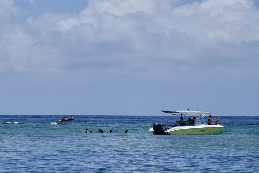 People swimming and snorkeling in Rosario Islands next to a boat.
