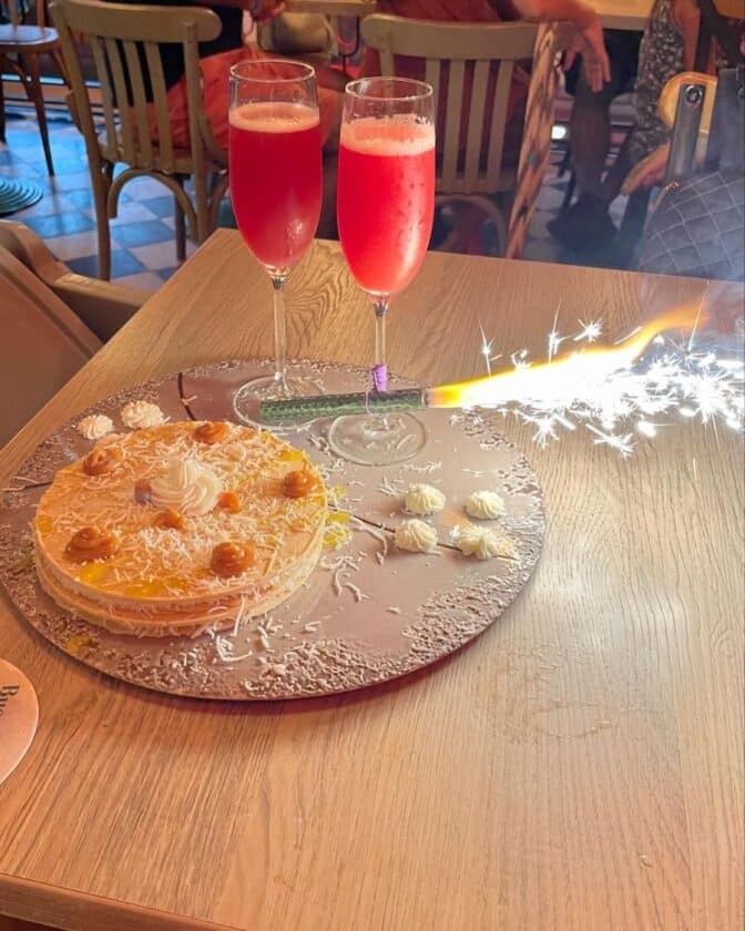 Photo of a cake with a sparkling candle and two champagne glasses on a table at the Buena Vida Marisquería Cartagena.