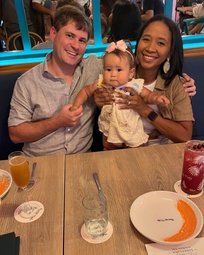 Photo of a couple holding an infant at a table at the Restaurant Buena Vida Cartagena with plates and drinks on the table in front.