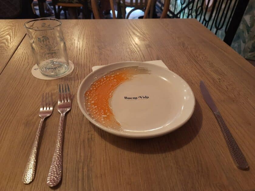 Photo of a plate that says Buena Vida with utensils and a glass on a table at Buena Vida Marisquería Cartagena.