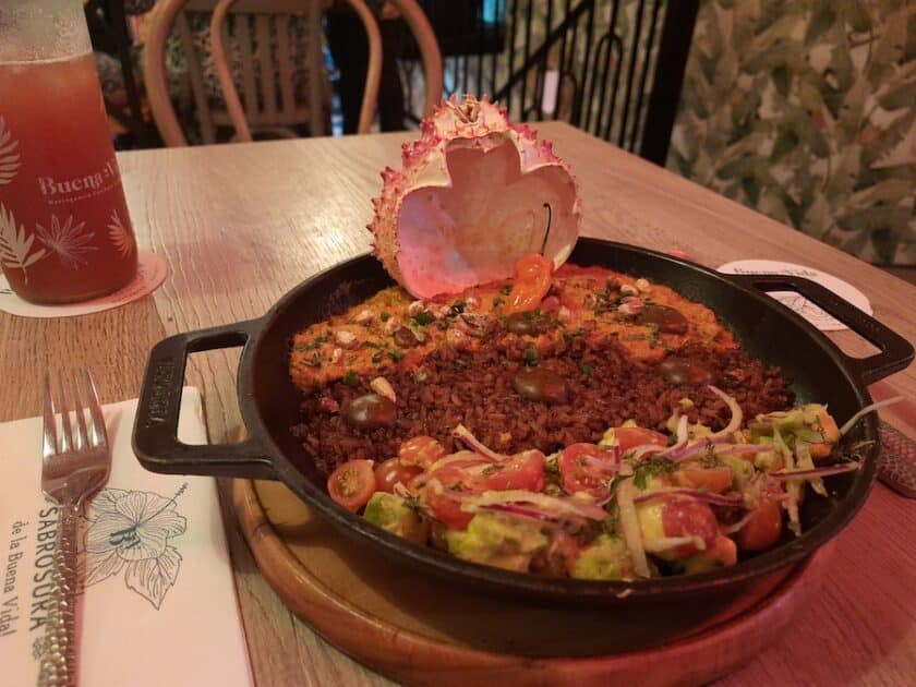 Photo of a cast iron skillet with food and a crab shell at the back.
