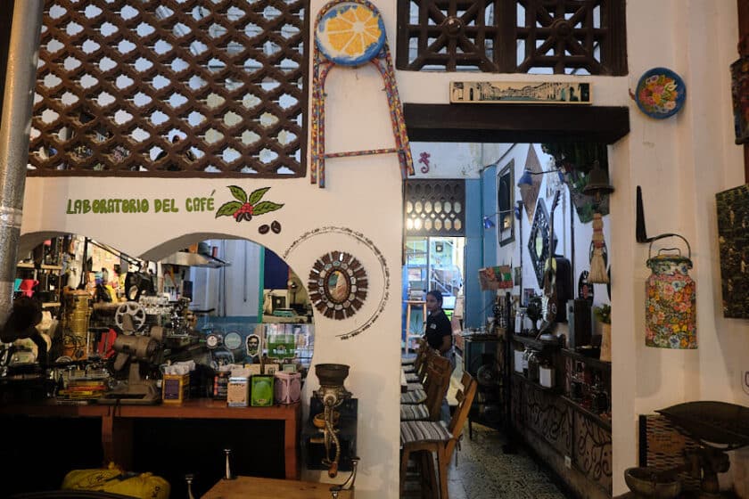 Photo of an archway into a kitchen with the words laboratorio de cafe above it and a entrance to the right.