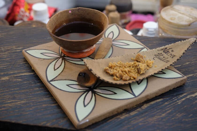 Photo of a small tile with a cup of coffee in a gourd and a small amount of unrefined sugar cane on the side.