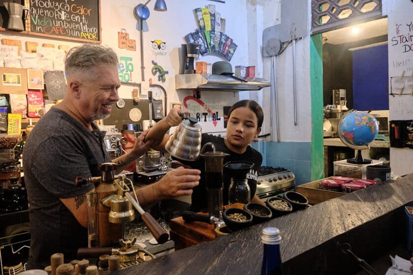 Photo of a girl pouring hot water into a coffee maker while a man looks on smiling during a Cartagena coffee tasting at Cafe del Mural.