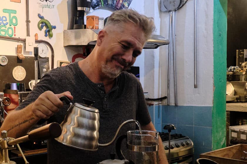 Photo of the owner of Café del Mural in Cartagena pouring water from a kettle into a French Press.