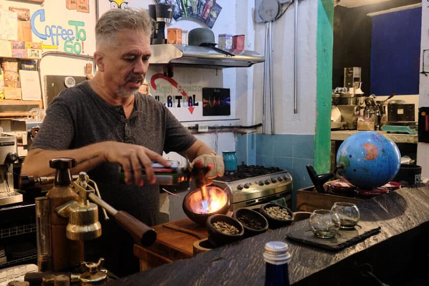 Photo of a man roasting coffee beans in a bowl using a blowtorch during a Cartagena coffee tasting at Café del Mural.