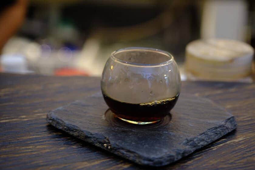 Photo of a circular glass of coffee on a black tile at Café del Mural in Cartagena, Colombia.