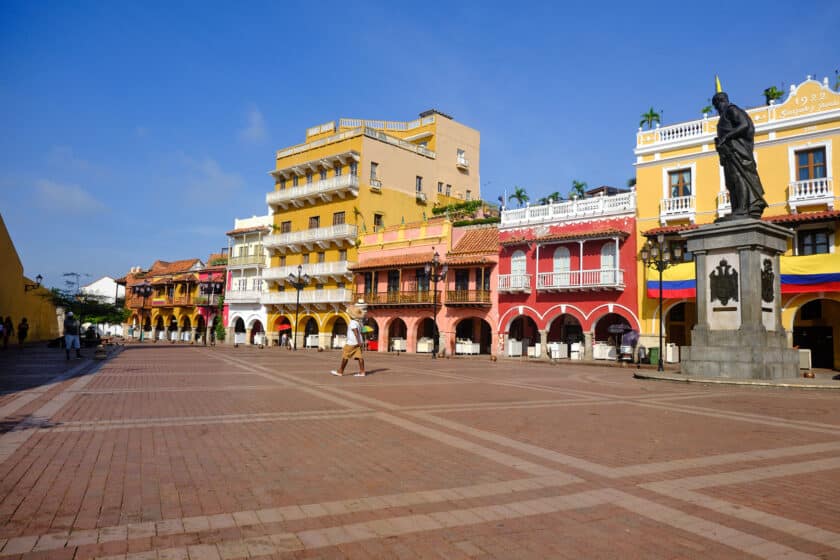 Large plaza with a statue and colorful buildings in the Cartagena, Colombia Old Town.