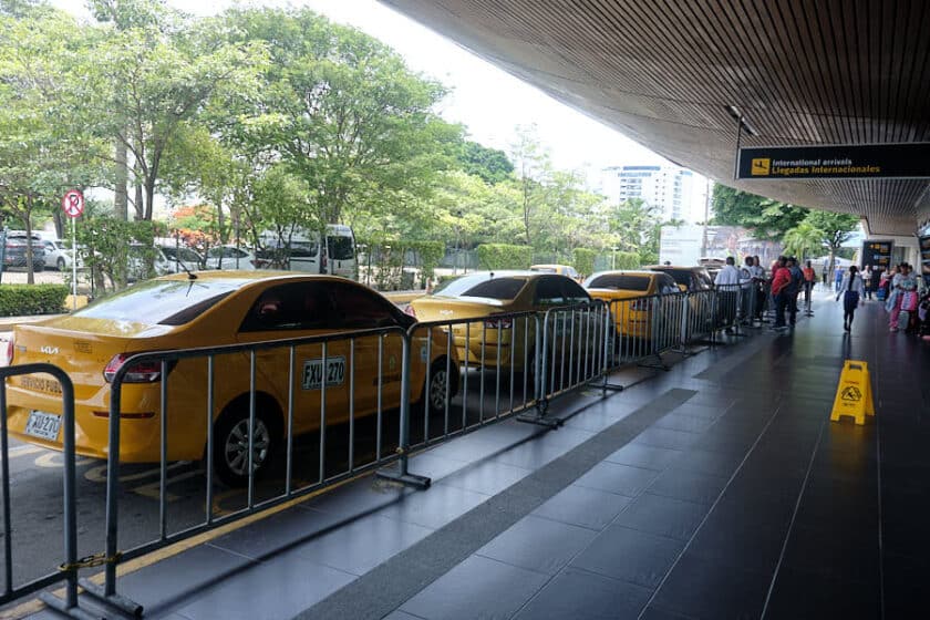 People asking how much is a taxi from Cartagena airport to the city next to a line of Cartagena airport taxis.