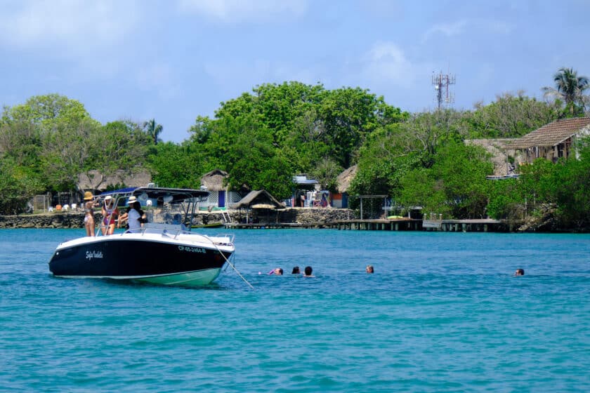 People dancing on and swimming next to a private rental boat to the Rosario Islands in Cartagena, Colombia.