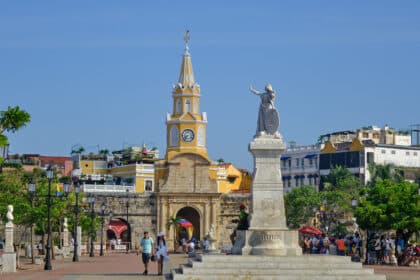 People walking by a statue and the clocktower in Cartagena de Indias, Colombia.
